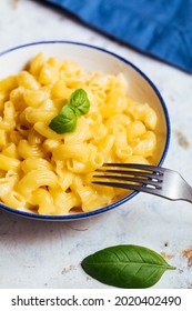 Classic Mac And Cheese On A Rustic White Wooden Background With Basil Leaves And Fork