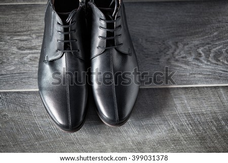 Classic male black leather shoes on wooden background