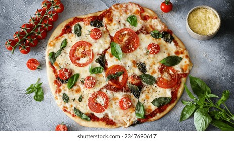 Classic Margherita pizza next to fresh basil, cherry tomatoes, and grated Parmesan on a rustic wooden table. Authentic Italian cuisine - Powered by Shutterstock