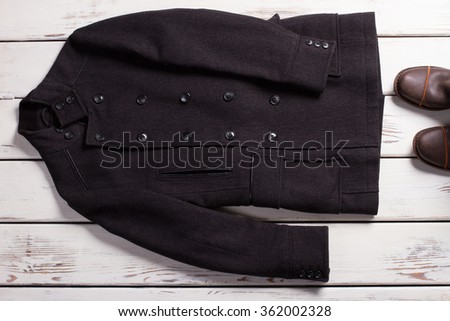 Classic men's coats and boots on a wooden background.