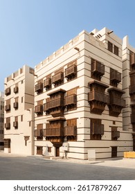 Classic Middle Eastern architecture featuring multiple wooden mashrabiya balconies on a beige building under clear blue sky at Jeddah in Saudi Arabia