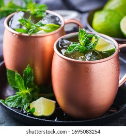 Classic Moscow Mule Cocktail With Green Lime, Mint, Ice In A Copper Mug On A Black Table.