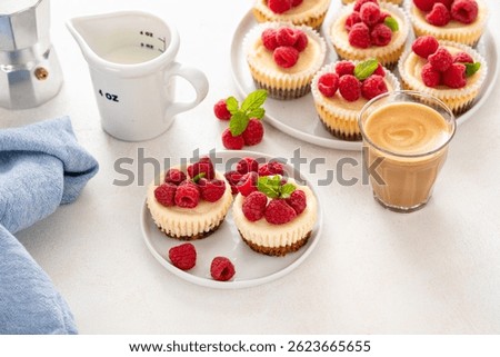 Classic New York cheesecakes in individual cups topped with fresh raspberry served with coffee