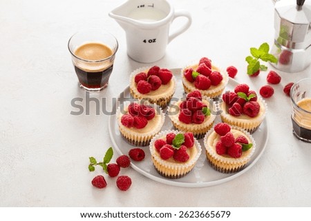 Classic New York cheesecakes in individual cups topped with fresh raspberry served with coffee