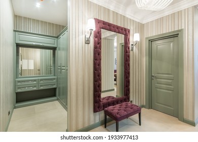 The Classic Olive Built-in Wardrobe In The Corner Of The Hall. A Mirror Hanging In Front Of The Entrance Door. A Purple Velvet Couch Standing In From Of The Mirror.