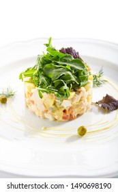 Classic Olivier Salad Or Russian Salad With Chicken Fillet, Quail Eggs, Pickles, Greens And Peas On White Plate Isolated. Traditional Christmas Salat Or Stolichny Salad On A White Plate In Restaurant