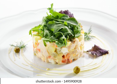 Classic Olivier Salad Or Russian Salad With Chicken Fillet, Quail Eggs, Pickles, Greens And Peas On White Plate Isolated. Traditional Christmas Salat Or Stolichny Salad On A White Plate In Restaurant