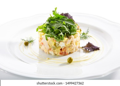 Classic Olivier Salad Or Russian Salad With Chicken Fillet, Quail Eggs, Pickles, Greens And Peas On White Plate Isolated. Traditional Christmas Salat Or Stolichny Salad On A White Plate In Restaurant