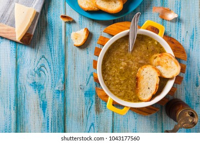 Classic Onion Soup With Croutons. Served In Yellow Bowl On Blue Boards. Top View.