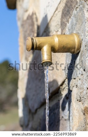 Classic open water faucet on a stone wall. Open vintage water faucet on a stone wall. water saving concept