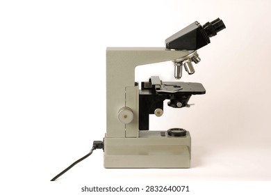 Classic optical microscope designed for laboratory observation and scientific research, featuring a sturdy metal frame, binocular viewing head, objective turret, adjustable stage and focusing mechanism.