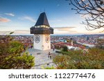 Classic panorama view of the historic city of Graz with famous Grazer Uhrturm clock tower in beautiful evening light at sunset, Styria, Austria