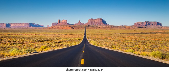 Classic panorama view of historic U.S. Route 163 running through famous Monument Valley in beautiful golden evening light at sunset on a beautiful sunny day with blue sky in summer, Utah, USA