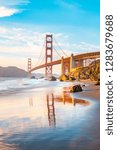 Classic panoramic view of famous Golden Gate Bridge seen from scenic Baker Beach in beautiful golden evening light on a sunny day with blue sky and clouds in summer, San Francisco, California, USA