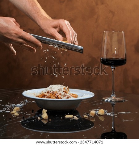 classic pasta spaghetti bolognese with a hat of parmesan on a black marble table with a glass of wine