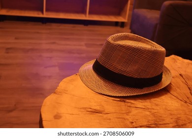 Classic patterned fedora hat placed on a rustic wooden surface in warm indoor lighting, close-up fashion accessory shot.