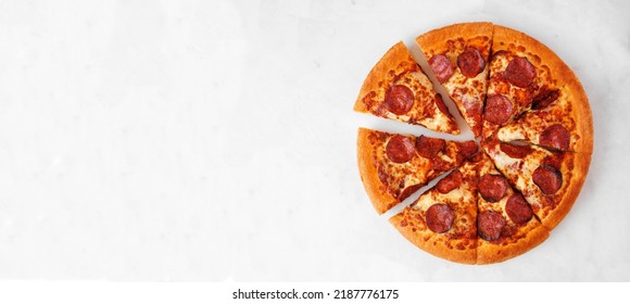 Classic Pepperoni Pizza With Cut Slices. Overhead View On A White Marble Banner Background. Copy Space.