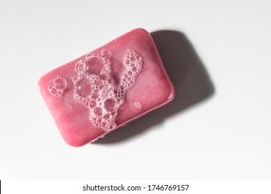 Classic Pink Bar Of Soap With Bubbles Shot From Above Top Down On A Clean White Surface.