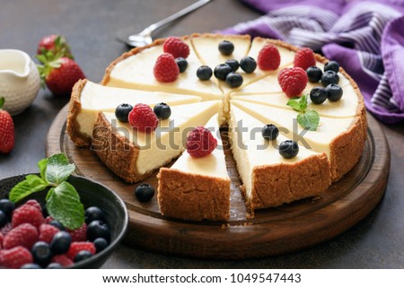 Classic plain New York Cheesecake sliced on wooden board, closeup view, selective focus