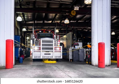 Classic powerful diesel big rig red semi truck with grille guard is being serviced in a specialized repair through shop equipped for semi trucks tractors safety and timely repairs and maintenance