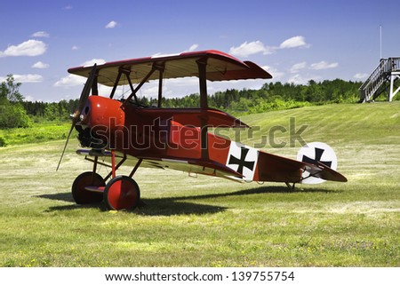Classic Red Barron Fokker Dr.1 triplane on grass runway.