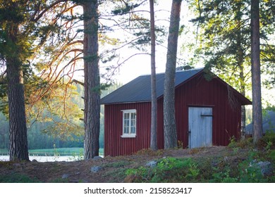 Classic Red Cabin In A Forest Next To A Beautiful Calm Swedish Lake In The Nordic Summer