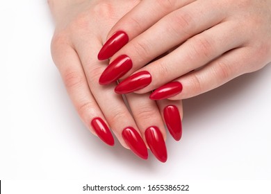 Classic red nails. Red manicure on long sharp nails closeup on a white background. Shape nails stilettos. Gel nails.