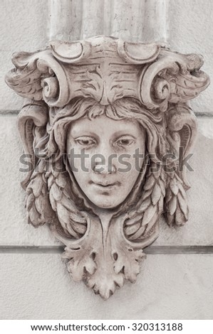 Classic roman head sculpture mounted on wall.