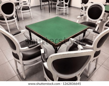 Classic room for Bridge playing game. Table covered with green tablecloth. Vintage wooden chairs. Game over. Nobody is here
