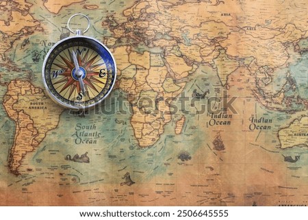 Classic round compass on background of old vintage map of world as symbol of tourism with compass, travel with compass and outdoor activities with compass