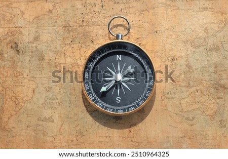 Classic round compass on background of old vintage map of world as symbol of tourism with compass, travel with compass and outdoor activities with compass