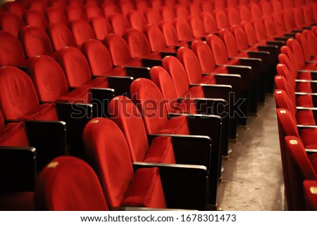 Classic rows of empty reddish seats in theatre. Hall without visitors. Shallow depth of field