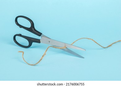 Classic scissors cutting rope on a blue background. Minimal business concept.