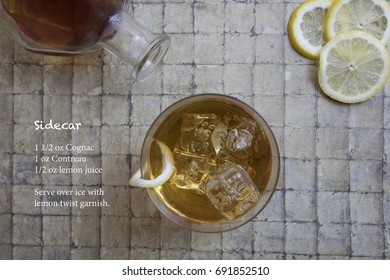 Classic Side Car Cocktail Garnished With Lemon Twist Over Ice And Recipe With Bottle And Lemon Slices.