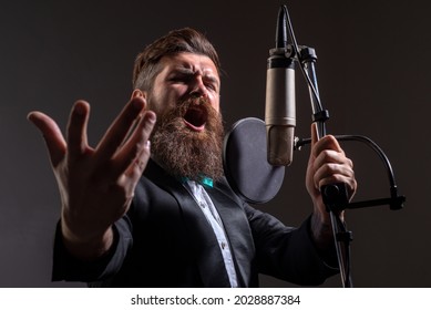 Classic singer in suit. Handsome man in recording studio. Music performance vocal. Singer singing song with a microphone.