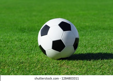 Classic Soccer Ball Lies On The Bright Green Grass On The Football Field At A Sports Stadium Close-up In A Large Sports Center For Football Players. Ready Idea For Your Text And Design