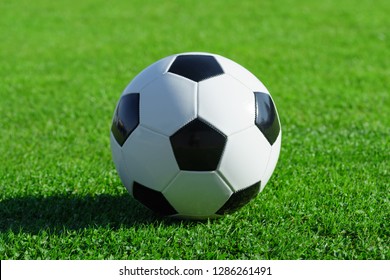 Classic Soccer Ball Lies On The Bright Green Grass On The Football Field At A Sports Stadium Close-up In A Large Sports Center For Football Players. Ready Idea For Your Text And Design