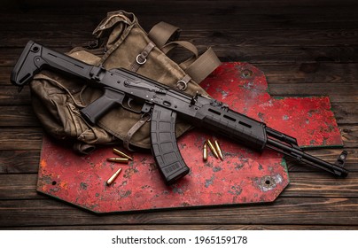 A Classic Soviet Military Rifle AK In A Modern Body Kit. The Carbine And Cartridges To It Are On Near The Military Backpack And The Target For Shooting. Weapons On A Wooden Table.