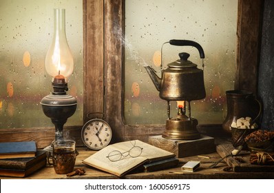 Classic still life with hot tea pot placed with illuminated vintage lamp, old books, cup of tea on rustic wooden table.  - Shutterstock ID 1600569175