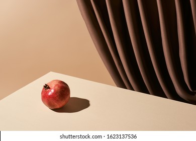 Classic Still Life With Pomegranate On Table Near Curtain Isolated On Beige