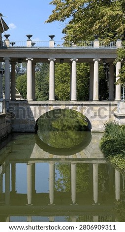 Classic stone bridge spanning over a calm pond in a green park