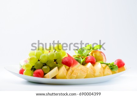 classic summer Italian food. Beautifully decorated fruit platter with watermelon, melon, apricot and grapes on a white plate, light background