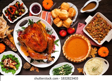 Classic Thanksgiving Turkey Dinner. Above View Table Scene On A Dark Wood Background. Turkey, Mashed Potatoes, Dressing, Pumpkin Pie And Sides.