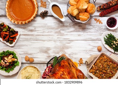 Classic Thanksgiving turkey dinner. Top down view frame on a rustic white wood background with copy space. Turkey, mashed potatoes, dressing, pumpkin pie and sides.
