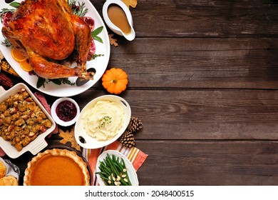 Classic Thanksgiving turkey dinner. Top down view side border on a dark wood background with copy space. Turkey, mashed potatoes, stuffing, pumpkin pie and sides.