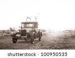 Classic truck (1928) driving on a dusty road in the desert.