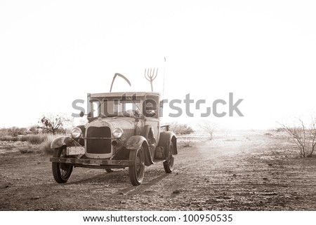 Classic truck (1928) driving on a dusty road in the desert.