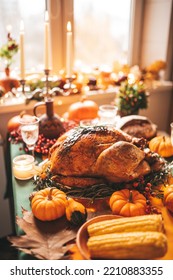 Classic USA Thanksgiving Day Dinner With Holiday Autumn Decor And Candles. Family Dining Room Table Set With Delicious Golden Roasted Turkey On Platter Garnished Rosemary And Fresh Small Pumpkins