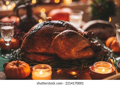 Classic USA Thanksgiving Day Dinner With Holiday Autumn Decor And Candles. Family Dining Room Table Set With Delicious Golden Roasted Turkey On Platter Garnished Rosemary And Fresh Small Pumpkins