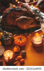 Classic USA Thanksgiving Day Dinner With Holiday Autumn Decor And Candles. Family Dining Room Table Set With Delicious Golden Roasted Turkey On Platter Garnished Rosemary And Fresh Small Pumpkins